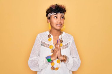 Genç, Afro-Amerikan Afro-Amerikan, güneş gözlüğü takan, aksesuar takan, yalvaran ve dua eden, yüzünde umut ifadesi olan, çok duygusal ve endişeli bir kadın. Yalvarıyorum..