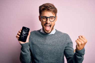 Sakallı, gözlüklü, kırık ve çatırdayan akıllı telefonlu genç adam gururla bağırıyor ve zaferi ve başarıyı kutluyor.