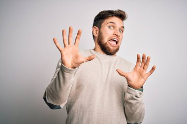 Sakallı, mavi gözlü, korku ifadesinden korkan, sıradan süveter giyen genç, yakışıklı sarışın adam. Ellerinle hareket etmeyi kes, şok içinde bağır. Panik konsepti.