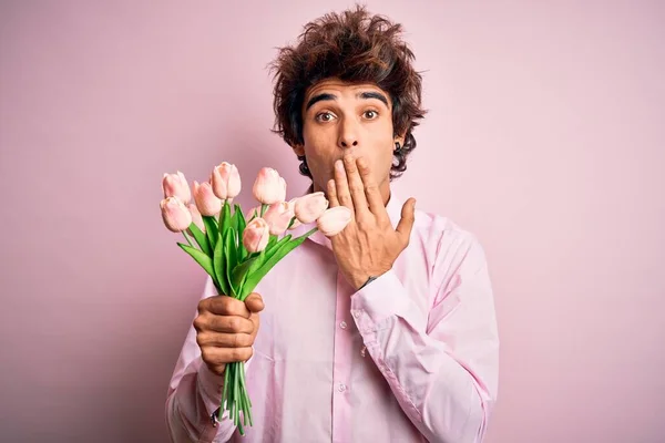 Молодой Красивый Мужчина Держащий Цветы Стоящие Над Изолированным Розовым Фоном — стоковое фото