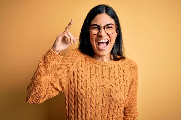 若い美しいヒスパニック系の女性は 成功したアイデアを指を指して黄色の隔離された背景に眼鏡をかけて 興奮し 第一番 — ストック写真