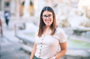 Mutlu ve kendinden emin gülümseyen genç ve güzel bir kadın. Kasaba caddesinde yüzünde gülümsemeyle dikilirken