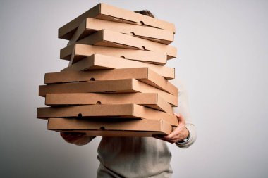 Teslimatçı, izole edilmiş beyaz arka planda duran bir yığın İtalyan pizzasını elinde tutuyor.