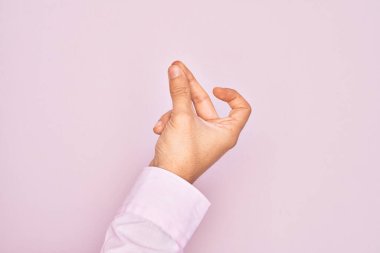 İzole edilmiş pembe arka planda parmaklarını gösteren beyaz bir gencin eli. Başarı için parmaklarını şıklatıyor, kolay ve elinle sembolü tıklatıyor.