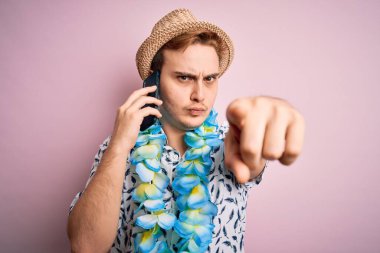 Tatilde şapkalı genç bir adam ve Hawai Lei Lei 'li akıllı telefondan konuşuyor kamerayı işaret ederek konuşuyor ve sen kendine güvenen ciddi bir hareket yapıyorsun.