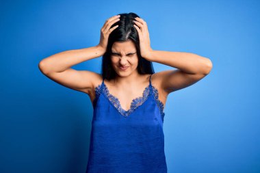 Zarif ve rahat mavi iç çamaşırı giyen genç, güzel esmer kadın. Baş ağrısı, çaresiz ve stresli. Ağrı ve migren yüzünden. Ellerini başının üstüne koy..