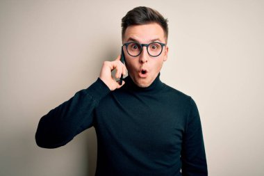 Yakışıklı, beyaz bir adam akıllı telefondan konuşuyor. Şaşırmış bir yüzle korkmuş, korku ifadesinden korkmuş ve heyecanlı.