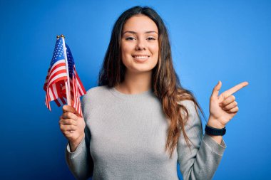 Genç, güzel, vatansever kadın elinde Amerikan bayrağı tutarak 4 Temmuz 'u çok mutlu bir şekilde kutluyor.