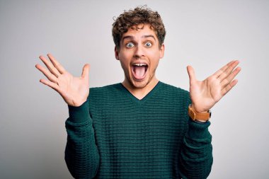 Sarışın, kıvırcık saçlı, yeşil kazaklı, beyaz arka planda çılgın kutlamalar yapan genç ve yakışıklı bir adam. Kolları havada ve gözleri açık bir şekilde heyecanla haykırıyor. Kazanan konsept