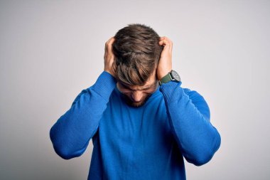 Sakallı, mavi gözlü, başağrısı yüzünden acı çeken, çaresiz ve stresli bir süveter giyen genç yakışıklı sarışın adam. Ellerini başının üstüne koy..