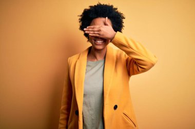 Kıvırcık saçlı, sarı ceketli, gülümseyen ve gülen güzel Afro-Amerikan iş kadını. Kör kavram.