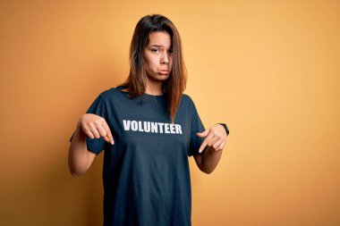 Genç ve güzel esmer kız gönüllü olarak tişört giyip gönüllü olarak mesaj yolluyor üzgün ve üzgün görünüyor, parmaklarıyla yön gösteriyor, mutsuz ve depresif..
