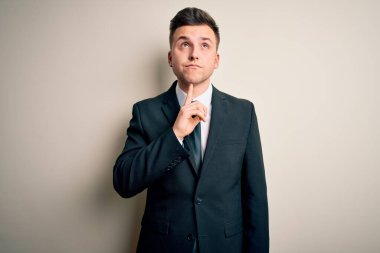 Zarif takım elbiseli ve kravatlı genç yakışıklı iş adamı izole edilmiş arka planda şüpheye odaklanmıştı. Parmakları çenesinde ve yukarı bakıyordu.