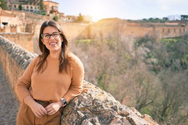 Genç, güzel, esmer, gözlüklü, mutlu ve kendinden emin bir kadın. Yüzünde tebessümle şehrin duvarına yaslanarak duruyorum.