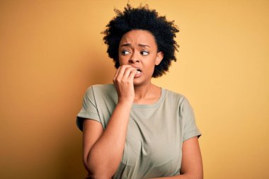 Kıvırcık saçlı, rahat tişörtlü, gergin ve elleri ağızdan tırnak yiyen güzel Afro-Amerikan kadın. Endişe sorunu.