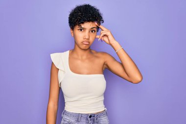 Güzel, Afro-Amerikan Afro-Amerikan bir kadın mor arka plan üzerine gündelik tişört giyiyor. Alnındaki sorun yüzünden endişeli ve stresli. Kriz için endişeli.