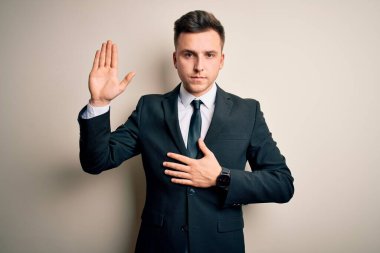 Zarif takım elbiseli ve kravatlı genç bir iş adamı, izole bir geçmişin üzerine yemin ederek, el pençe divan durarak ve el pençe divan durarak sadakat yemini ederek,