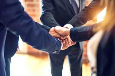 Bir grup işçi ellerini ofiste birleştirip bir daire çiziyor..