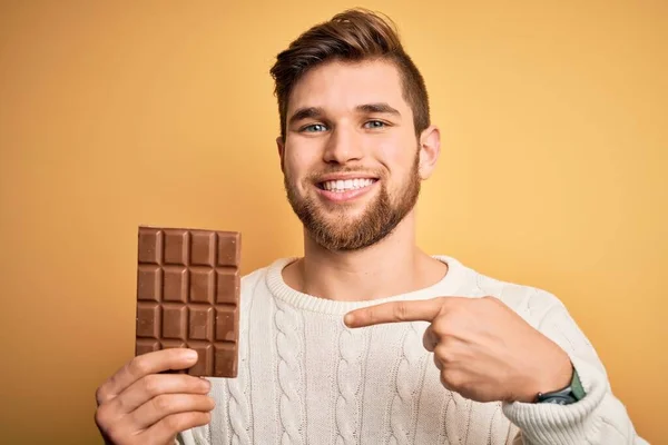 Jovem Loiro Com Barba Olhos Azuis Segurando Barra Chocolate Sobre — Fotografia de Stock