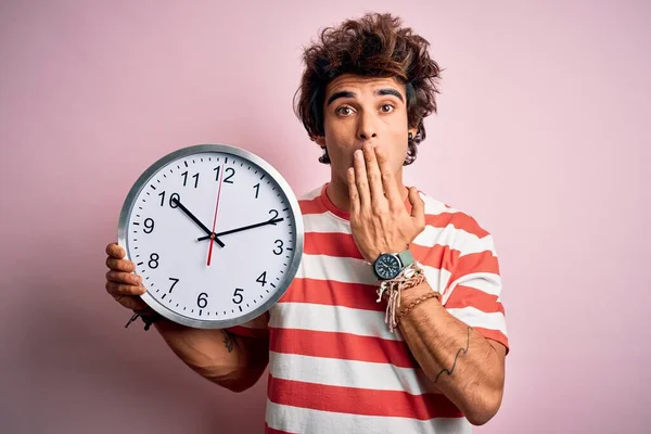 Joven Hombre Guapo Sosteniendo Gran Reloj Pie Sobre Boca Cubierta —  Fotos de Stock