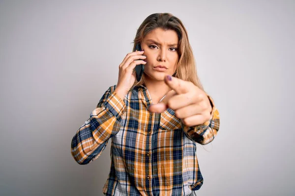 美しいブロンドの女性は カメラとあなたに指で指差す白い背景の上にスマートフォンで会話をしています 手のサイン 正とフロントからの自信を持ってジェスチャー — ストック写真