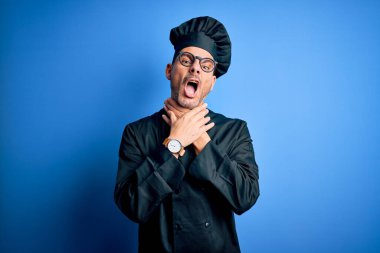 Genç, yakışıklı aşçı üniforması ve izole edilmiş mavi arka planda şapka giyen bir adam boğularak ölüyor çünkü acı verici bir boğulma. Sağlık problemi. Boğulma ve intihar konsepti.