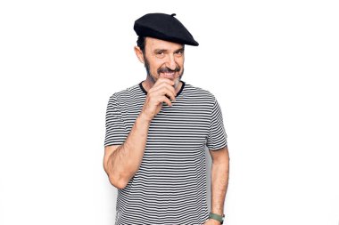 Orta yaşlı, çizgili tişört giyen ve beyaz arka planda Fransız beresi takan yakışıklı adam kameraya kolları çapraz ve çenesi açık gülümsüyor. Olumlu düşünüyorum..