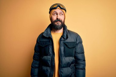 Sakallı, kar maskeli, kar maskeli, kar maskeli yakışıklı kayakçı. Gülümsüyor ve uzaklara bakıyor..