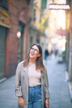 Mutlu ve kendinden emin gülümseyen genç ve güzel bir kadın. Kasaba caddesinde yüzünde gülümsemeyle dikilirken