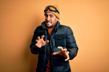 Sakallı, kar maskesi takan, kar maskesi takan yakışıklı bir kayakçı. Tiksinti reaksiyonu yüzünden tiksinti ve tiksinti ifadesi takınıyor..