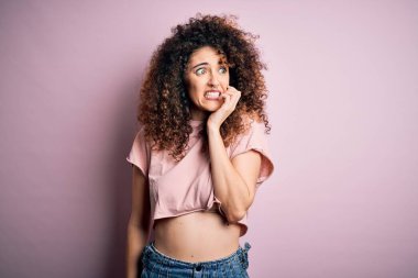 Kıvırcık saçlı, piercingli, sıradan pembe tişörtlü, stresli ve gergin görünen elleri ağızdan tırnak yiyen güzel bir kadın. Endişe sorunu.