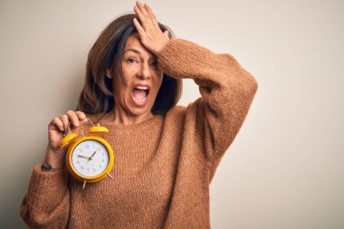 Orta yaşlı esmer kadın klasik çalar saati izole edilmiş arka planda tutuyordu. Hatayla el ele tutuşurken şaşırmıştı. Hatayı hatırla. Unuttum, kötü hafıza konsepti.