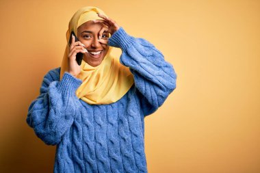 Afro-Amerikan kadın, Müslüman başörtüsü takıyor, akıllı telefondan konuşuyor, gülümsüyor ve gülümsüyor.