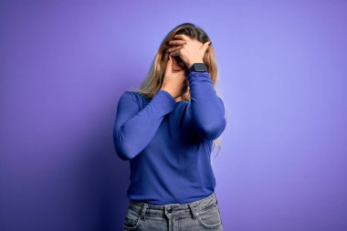 Genç, güzel, sarışın bir kadın, izole edilmiş mor arka plan üzerine gündelik tişört giyiyordu gözleri ve ağzı kapatıyordu, şaşırmış ve şok olmuştu. Duygularını gizliyor.