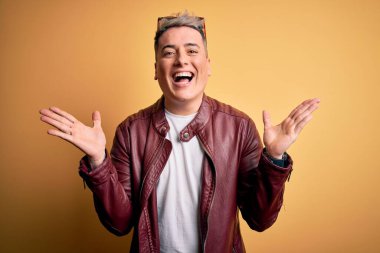 Sarı arka planda moda deri ceketi ve güneş gözlüğü takan genç, yakışıklı modern bir adam çılgın ve başarıyı kollarını kaldırıp heyecanla haykırarak kutluyor. Kazanan konsept