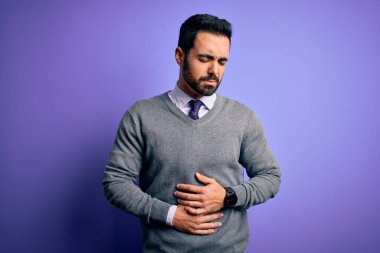 Sakallı yakışıklı bir iş adamı mor arka planda ayakta dikiliyor hazımsızlık, acı verici bir hastalık yüzünden midesi ağrıyor. Ache kavramı.