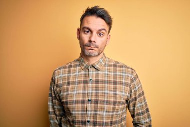 İzole edilmiş sarı arka planda dikilen sıradan tişörtlü genç ve yakışıklı bir adam depresif, sinirli ve korkmuş bir şekilde ağlıyor. Üzücü ifade.