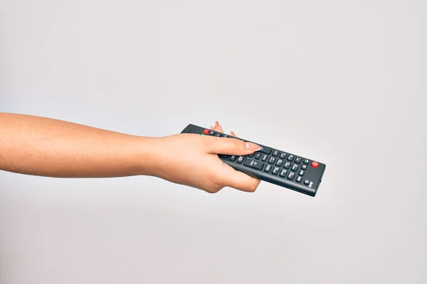 Hand of caucasian young woman changing television channel holding tv remote control over isolated white background