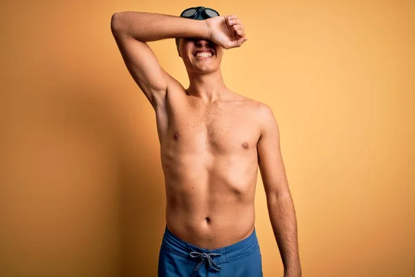 若いハンサムな男は水着を着て 陽気で面白い笑顔腕で目をカバー孤立した黄色の背景の上にキャップを泳ぐ ブラインドコンセプト — ストック写真