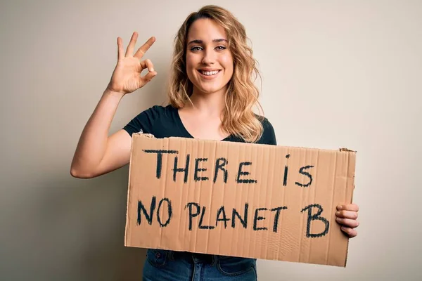 Young blonde activist woman asking for environment holding banner with planet message doing ok sign with fingers, excellent symbol