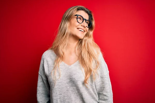 Giovane Bella Donna Bionda Indossa Maglione Occhiali Sfondo Rosso Isolato — Foto Stock