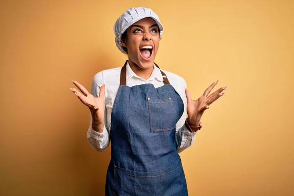 年轻的非洲裔美国女面包师 身穿围裙 头戴黄帽 疯疯癫癫地大喊大叫 带着咄咄逼人的表情和手臂 沮丧的概念 — 图库照片