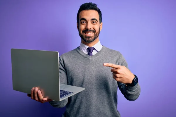 年轻英俊的大胡子商人 手指手画脚 手指手画脚地在紫色背景上用笔记本电脑干活 非常快乐 — 图库照片