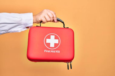 Beyaz arka plan üzerinde ilk yardım çantası taşıyan beyaz bir kadının eli.