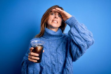 Genç, güzel, esmer bir kadın mavi arka planda kola serinletici bardakta içki içiyor. Elleri başının üstünde, utanç ve şaşkınlık dolu, sinirli ve hayal kırıklığına uğramış bir halde. Hata için korku ve üzüntü.