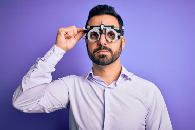 Mor arka planda optometri gözlüğü takan, sakallı, yakışıklı, optik bir adam.