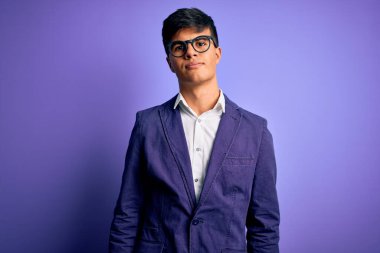 Ceket ve gözlük takan genç yakışıklı iş adamı. Mor arka planda. Uykulu ve yorgun görünüyor..