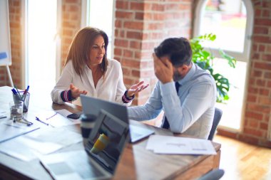 Mutlu ve kendinden emin gülümseyen iki orta yaşlı iş adamı. Ofiste dizüstü bilgisayarla gülümseyerek birlikte çalışıyoruz.