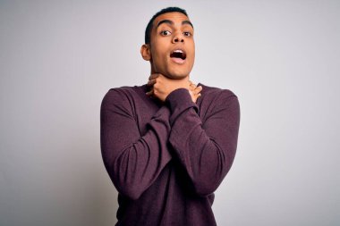 Beyaz arka plan üzerine gündelik kazak giyen genç ve yakışıklı Afro-Amerikan adam bağırıyor ve boğuluyor çünkü acı verici bir boğulma var. Sağlık problemi. Boğulma ve intihar konsepti.