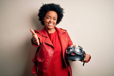 Kıvırcık saçlı, motosiklet kaskı takan, gülümseyen, dostça el sıkışan Afro-Amerikan motosikletli genç bir kadın. Başarılı bir iş..